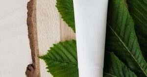 Eco Products - Top view of chestnut green leaf and mockup of skin care or hair care cosmetic product placed on wooden surface
