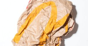 Reduce Waste - Top view of crumpled empty craft paper bag of fast food restaurant placed on white background illustrating recycle garbage concept