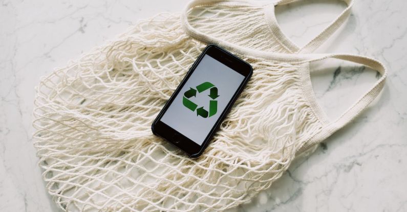 Sustainable Savings - Overhead of smartphone with simple recycling sign on screen placed on white eco friendly mesh bag on marble table in room