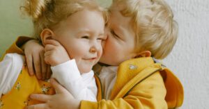 Baby Home - Cheerful little siblings hugging in armchair at home