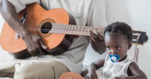 Family Band - Father and Daughter Playing Guitars on a Bed