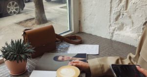 Relax Adventure - Crop of unrecognizable female tourist in casual wear surfing internet and flipping magazine while drinking coffee in sidewalk cafe