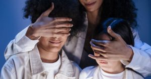 Parental Controls - Mother covering eyes of her children with hands against internet content on digital pad