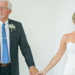Engaged Parent - Touched bride in white dress holding hands with senior father in elegant suit and wineglass of champagne during wedding day