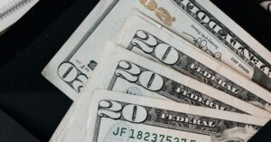 Budget Plan - Stack of dollars and black envelope with banknotes inside