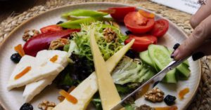 Cost Cutting - Woman Hands Holding Fork and Knife over Plate with Food